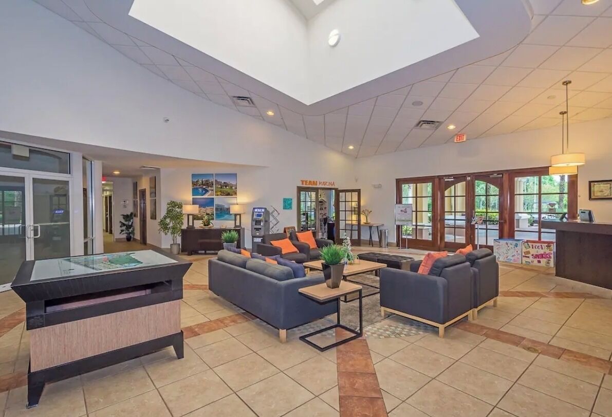 A spacious lobby with a reception desk, sofas, a coffee table, and a pool table.