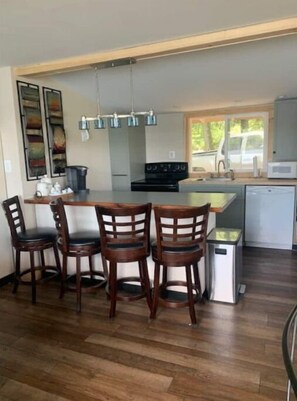 Enjoy cooking in this well-equipped kitchen with a central island, stove, and microwave, surrounded by comfortable seating for four.