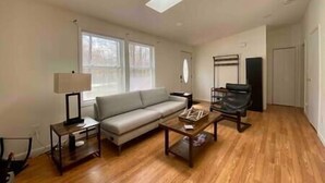 A living room with a sofa, coffee table, and lamp. There are windows and a door in the background. - Casa Vines (DrPocono Lake)