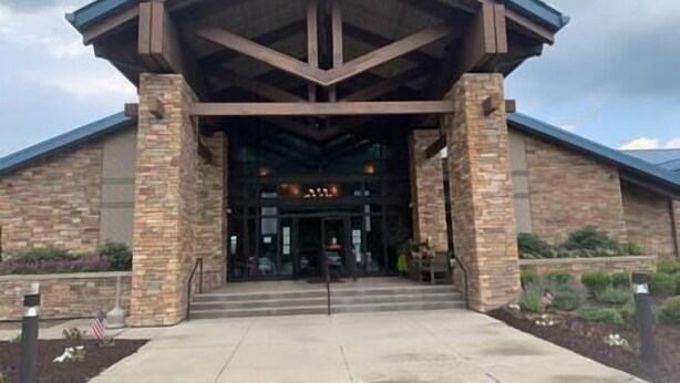 A building with a stone facade, a prominent entrance with steps, and a covered roof structure. - Casa Vines (DrPocono Lake)
