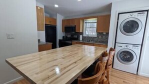 A kitchen with wooden cabinets, a double oven, and a built-in washer and dryer. - Casa Vines (DrPocono Lake)