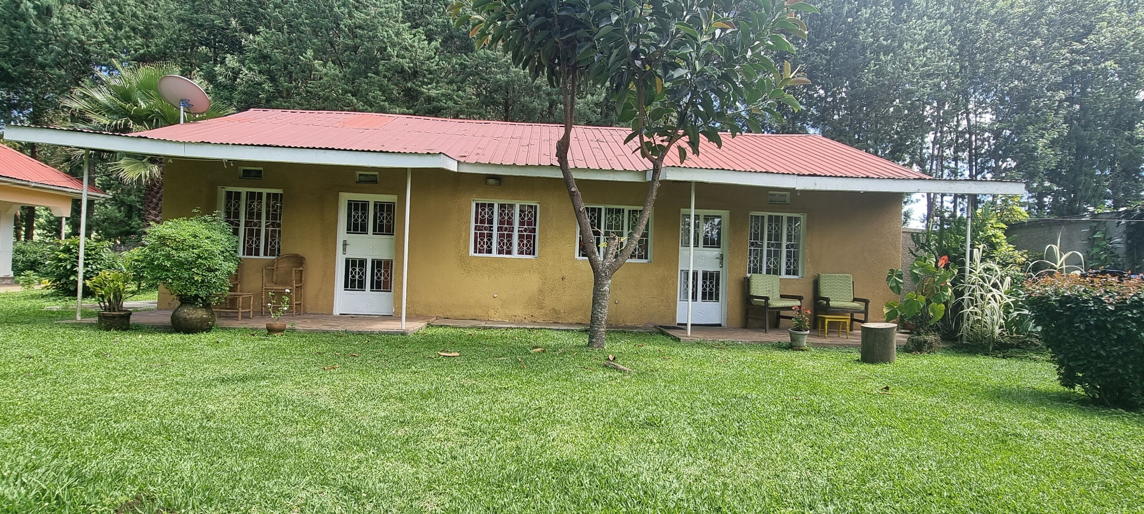 Un bâtiment jaune avec un toit rouge, une porte et des fenêtres. Il y a une petite pelouse devant.