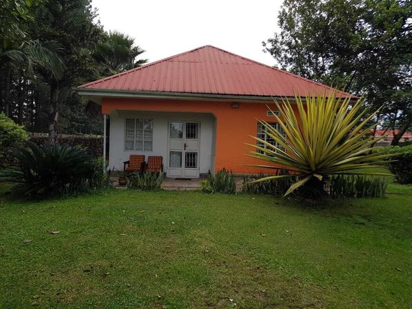 Une maison avec un toit rouge, une porte blanche et un petit porche avec deux chaises.
