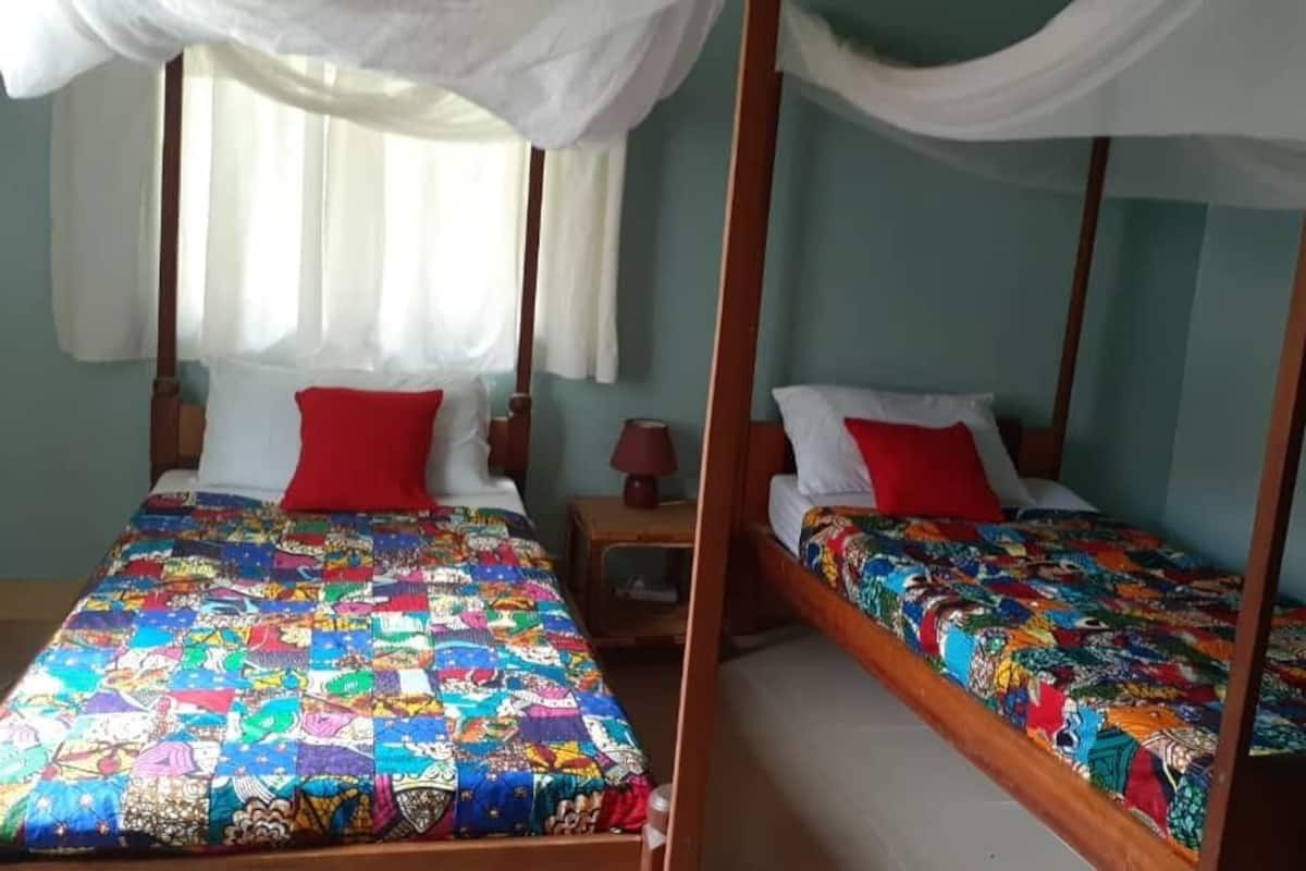 Ein Zimmer mit zwei Betten, jeweils mit Baldachin und farbenfroher Bettwäsche.
