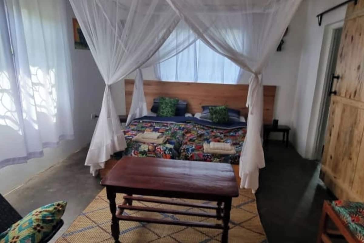 Ein Zimmer mit einem Bett unter einem Baldachin, einer Bank und einer Holztür.