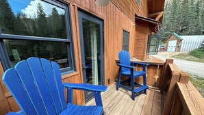 Una terraza de madera con dos sillas Adirondack azules y una mesita.