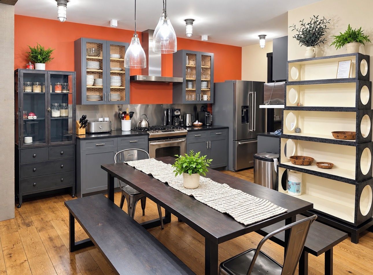 A modern kitchen with grey cabinets, a wooden dining table, and pendant lights.