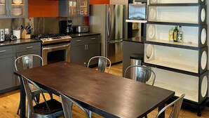 Una cocina moderna con una isla central, electrodomésticos de acero inoxidable e iluminación colgante.