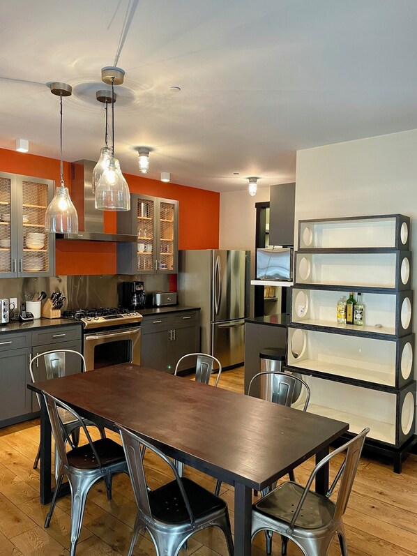 Una cocina moderna con una isla central, electrodomésticos de acero inoxidable e iluminación colgante.