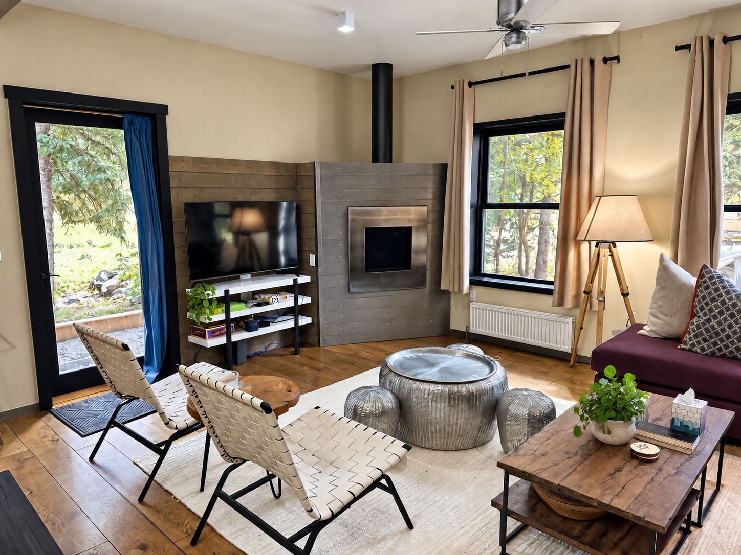 A modern living room with a flat-screen TV, a fireplace, a sofa, a coffee table, and a dining area.