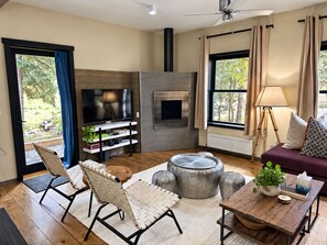 A modern living room with a flat-screen TV, a fireplace, a sofa, a coffee table, and a dining area.