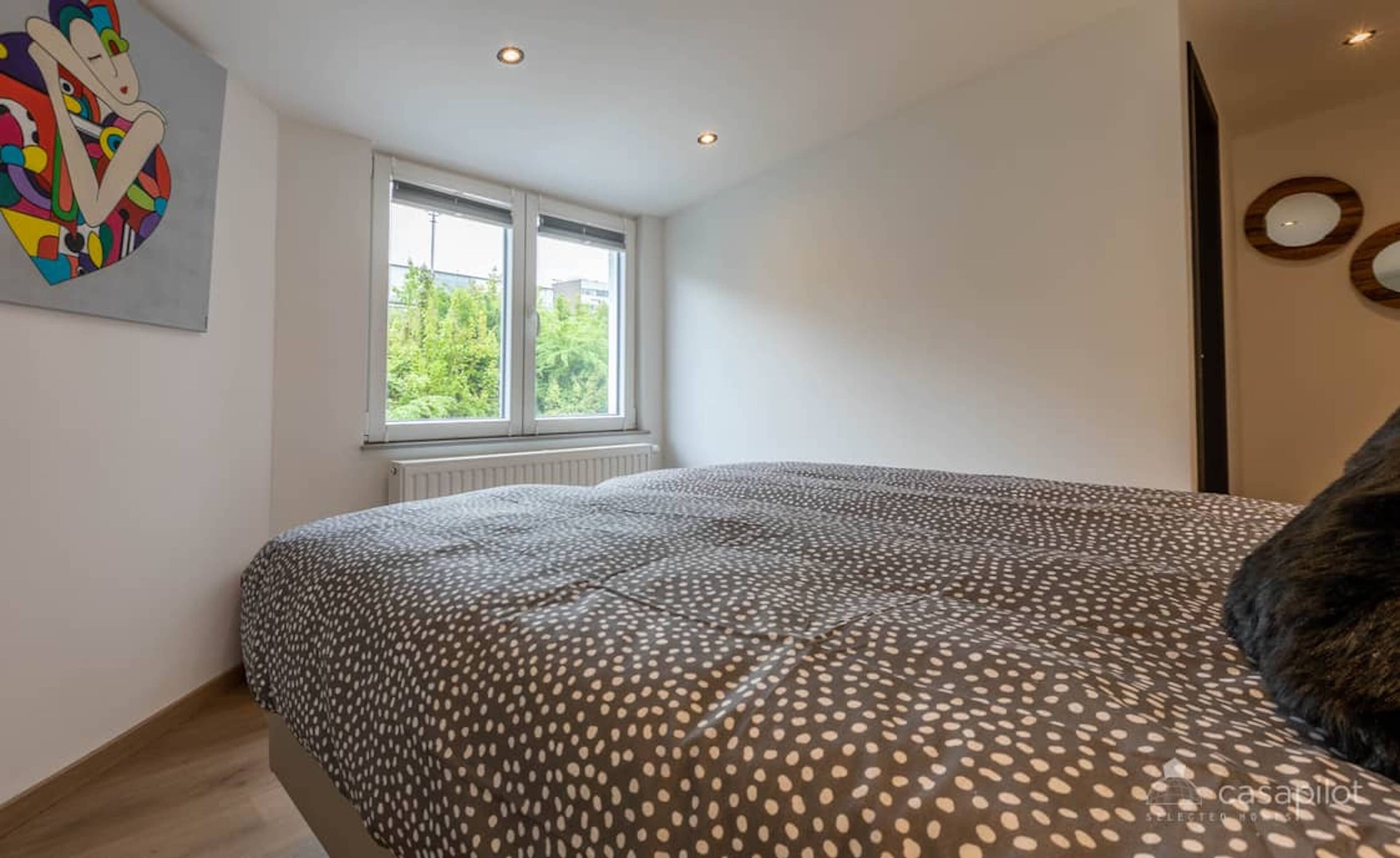 A bedroom with a bed, a window, and a radiator.