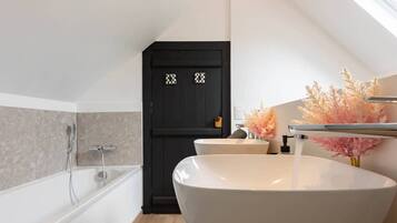A modern bathroom with a freestanding bathtub, a large white sink, and a black door with decorative patterns.