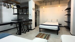 A compact hotel room with a kitchenette, a bed, and a small seating area.