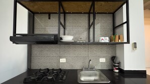 A modern kitchen with a black countertop, stainless steel sink, and gas stove.