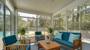 A sunroom with large windows, a pool, and outdoor seating. - Wilmington Rental ~ 4 Mi to Wrightsville Beach! (Wilmington)