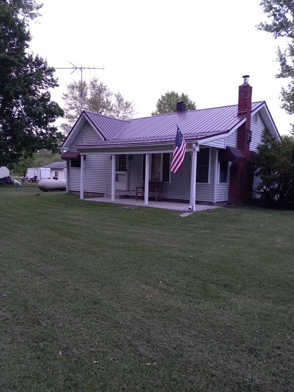 A single-story house with a porch, a chimney, and an American flag.