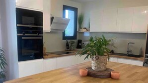 Una cocina moderna con una mesa de comedor de madera, electrodomésticos integrados y una planta en maceta.