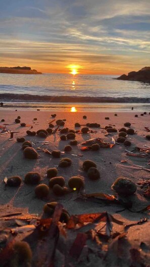 Ein Strand bei Sonnenuntergang mit verstreuten Gegenständen im Sand.