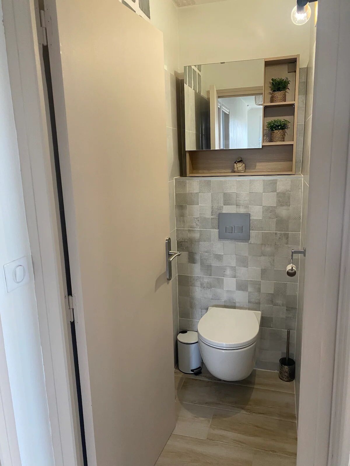 A compact bathroom with a toilet, a small trash bin, and a shower area.