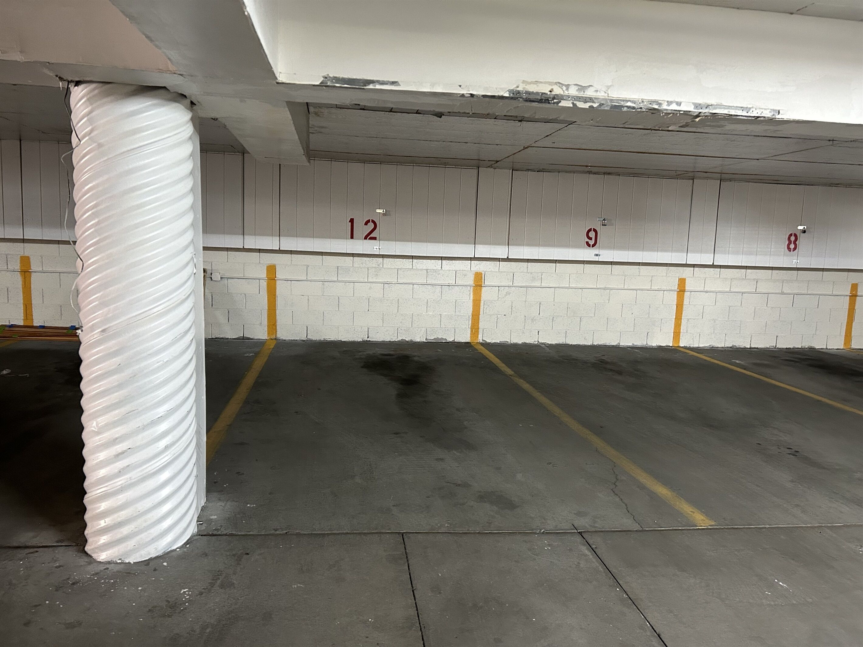 A parking garage with concrete floors, white walls, and numbered parking spaces.