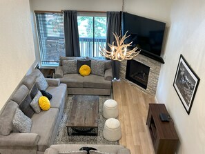 A living room with a sectional sofa, a fireplace, a mounted TV, and a wooden coffee table.