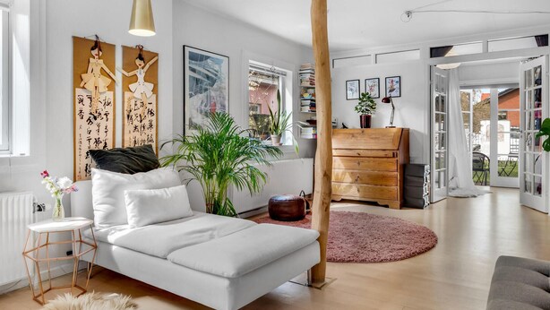 Ein modernes Wohnzimmer mit einem weißen Sofa, Holzmöbeln und einem großen Fenster.