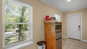 A kitchen with a wooden cabinet, a trash can, and a door.