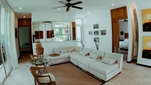 A spacious living area with a white sectional sofa, a glass coffee table, and a ceiling fan. - Villa Mangle Casa Boutique (Cartagena de Indias)