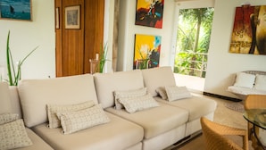 A modern living room with a beige sofa, wicker chairs, and artwork on the walls. - Villa Mangle Casa Boutique (Cartagena de Indias)