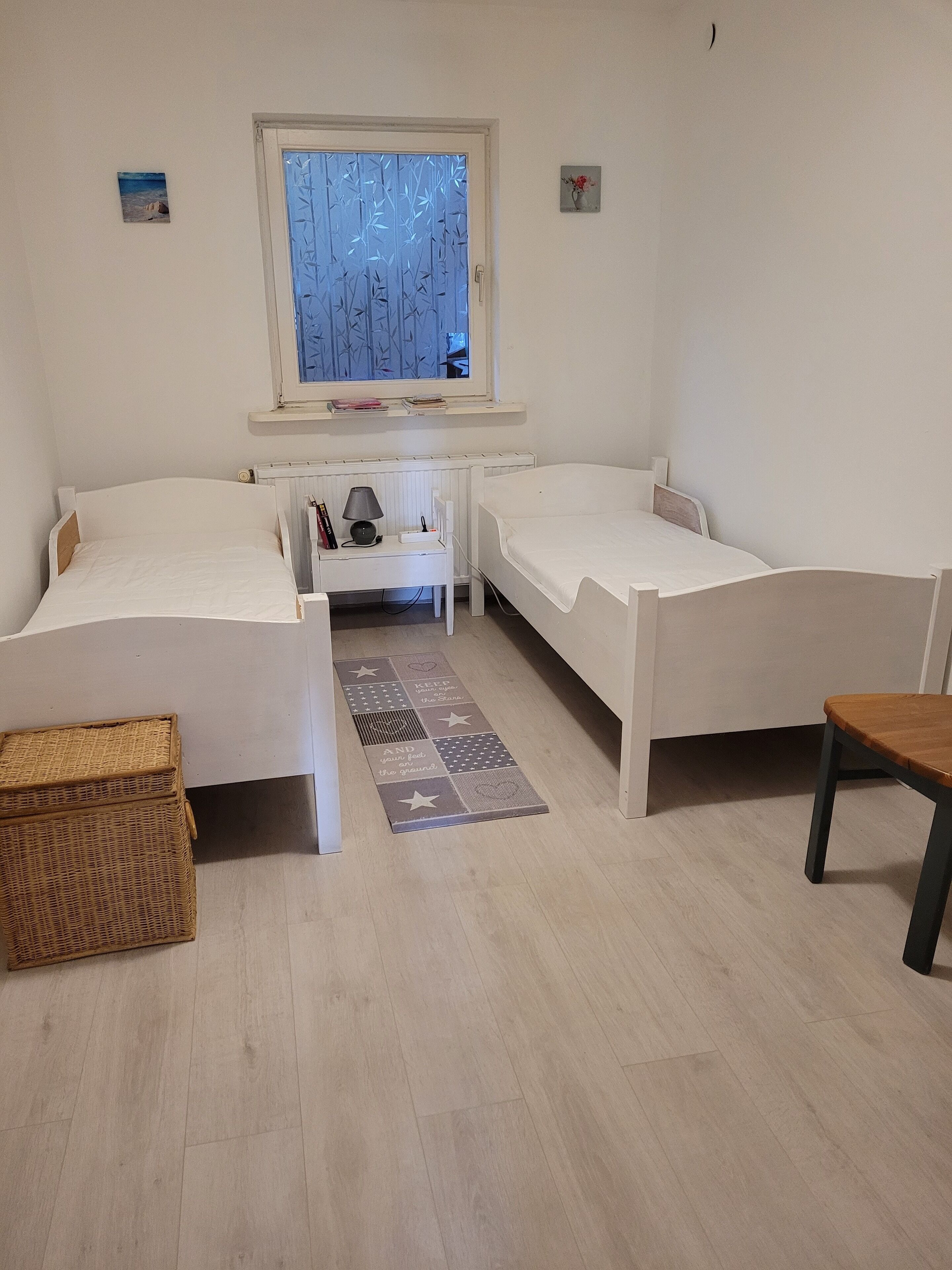 Ein Zimmer mit zwei Einzelbetten, einem kleinen Tisch, einem Fenster mit Blick und einer Heizung.