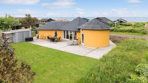 Ein Wohnhaus mit Terrasse, ein gelbes Gebäude und Blick auf das Meer.