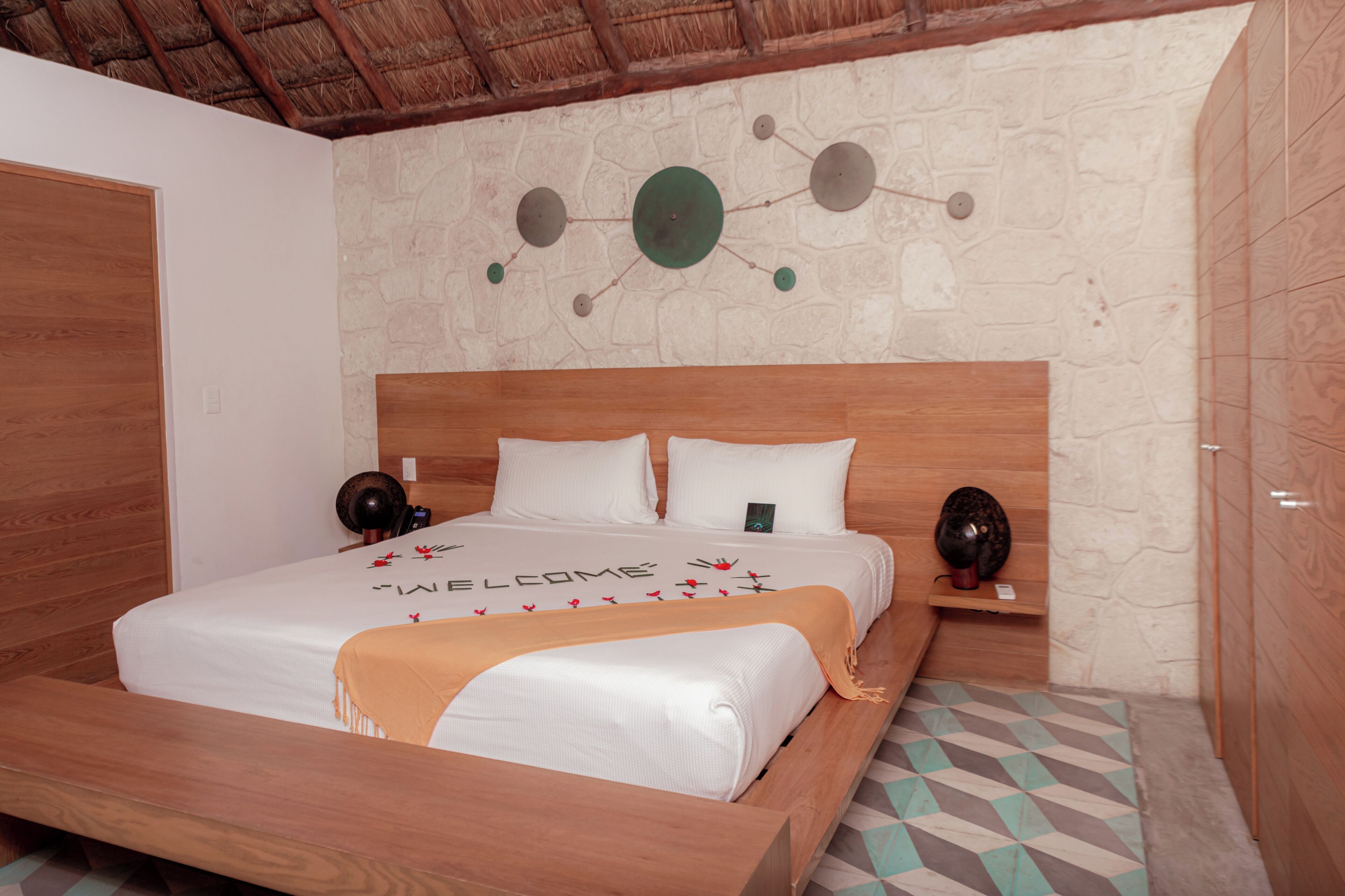 Un dormitorio con una cama de madera, una pared de piedra y un techo con diseño circular.