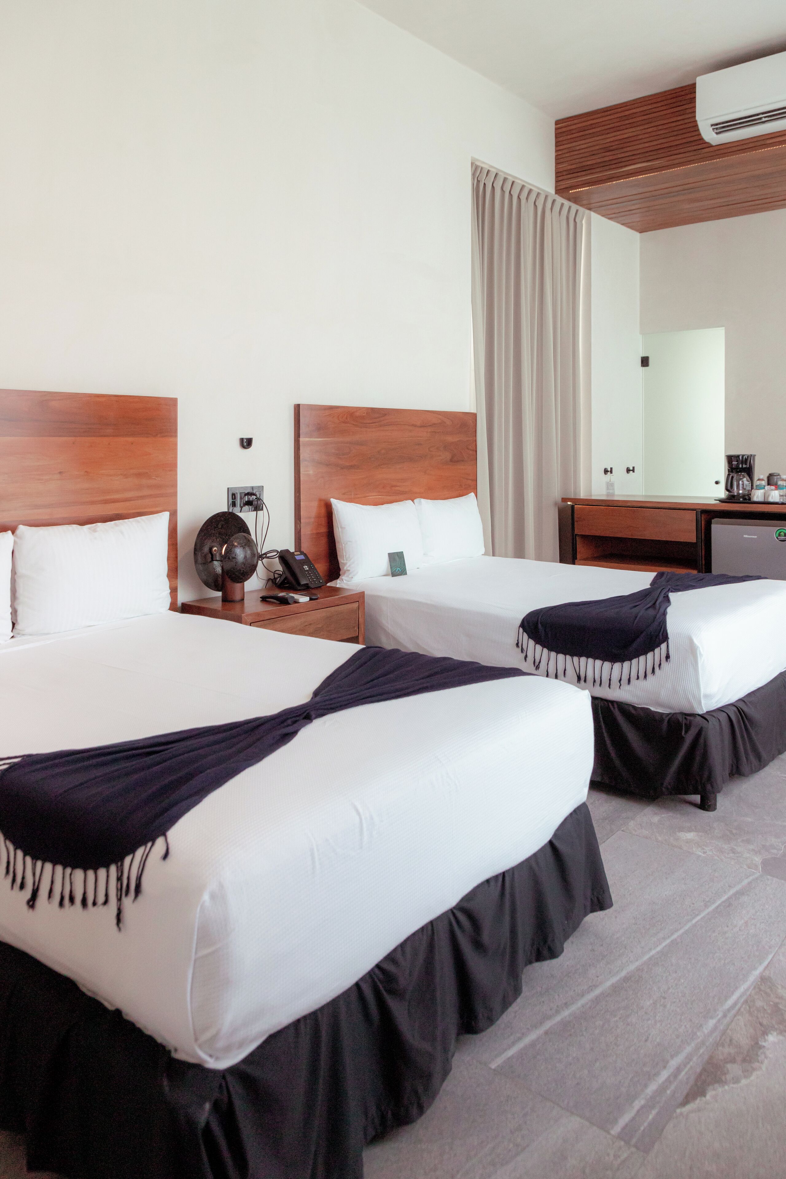 Una habitación de hotel con dos camas, cabeceros de madera, un escritorio y un espejo.