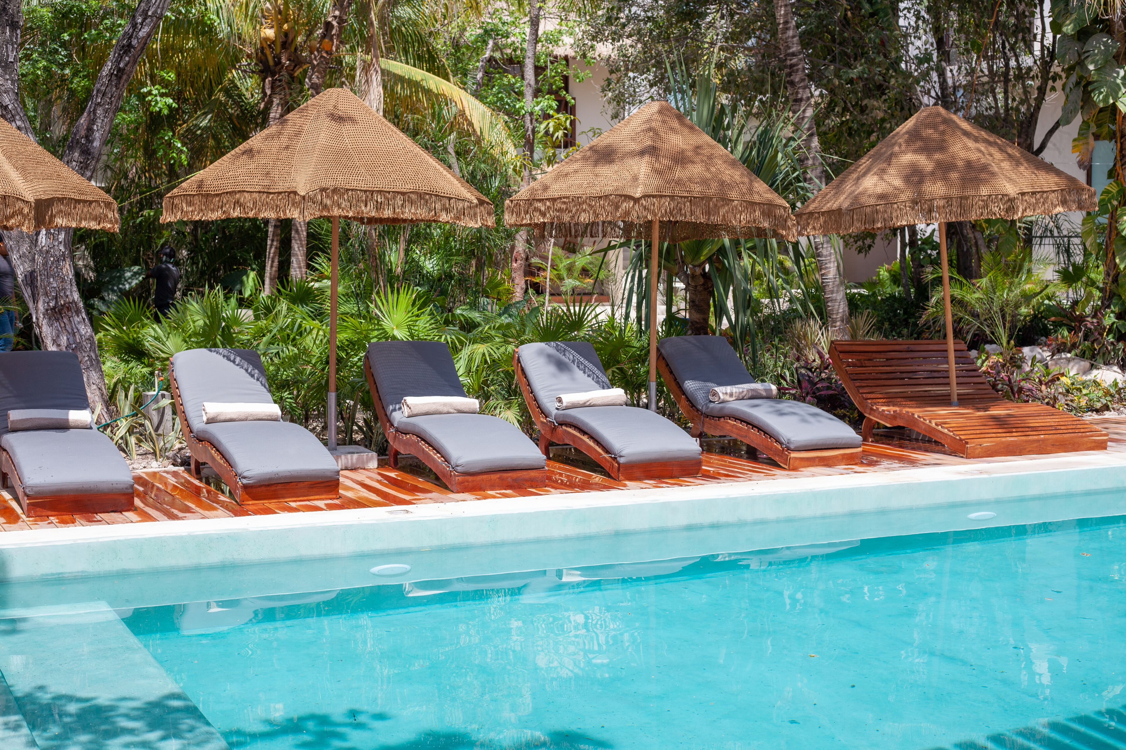 A poolside area with lounge chairs and thatched umbrellas.