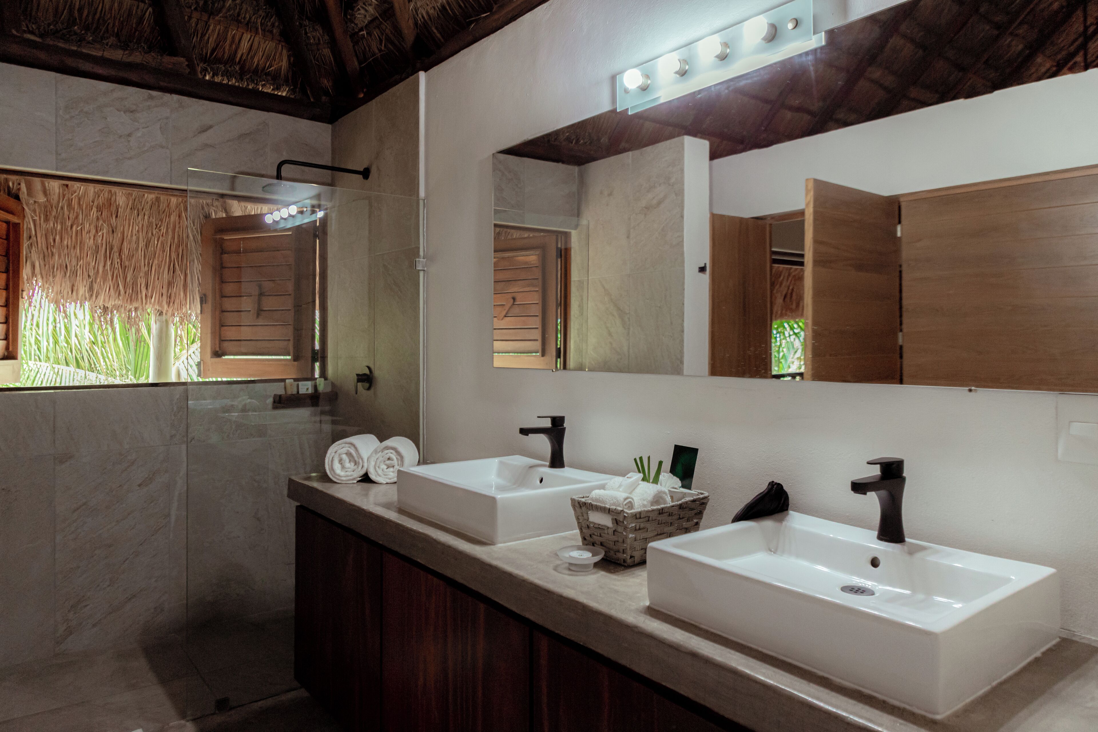 A modern bathroom with two sinks, a large mirror, and a shower area.