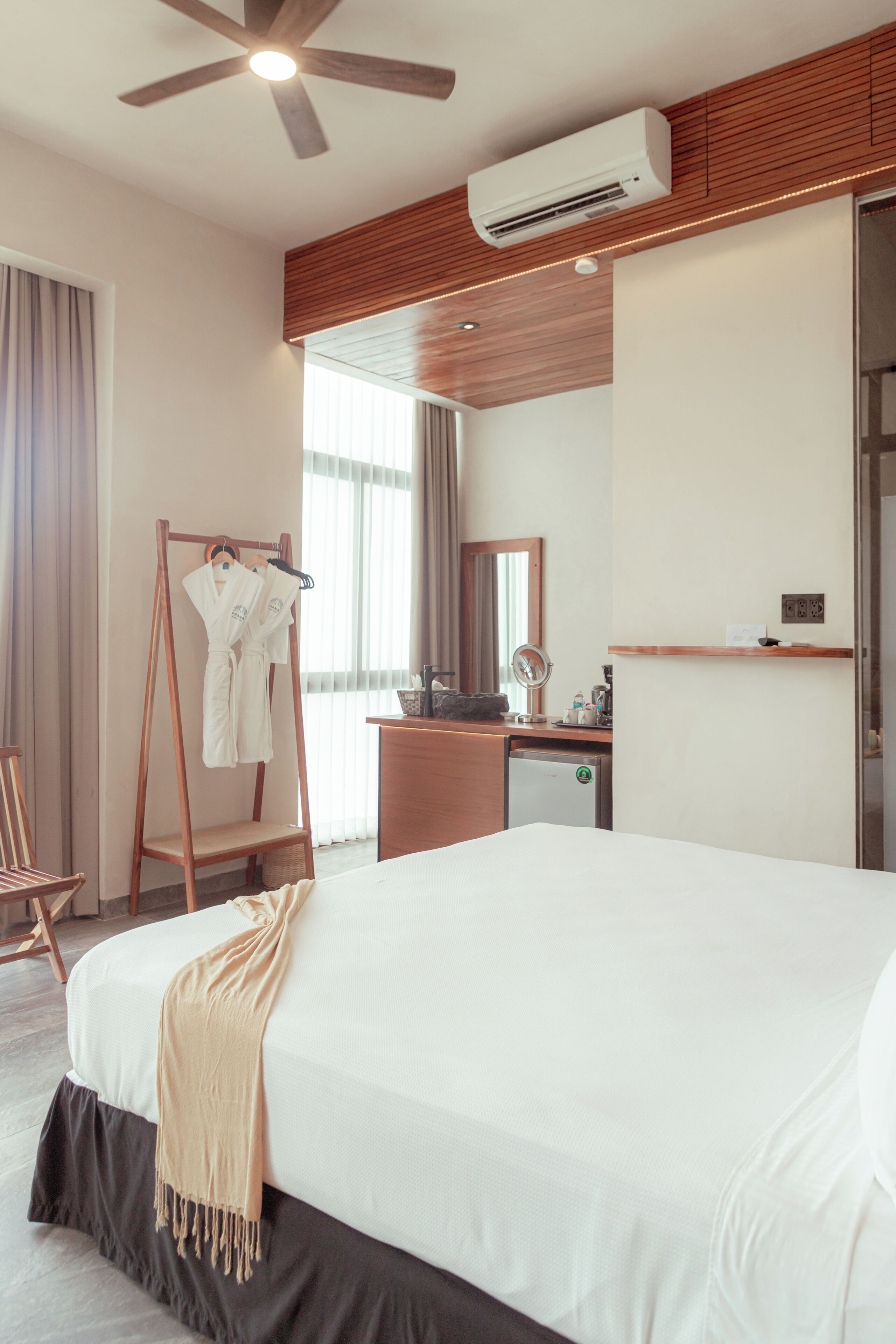 Habitación de hotel con una cama grande, un armario de madera, un escritorio con espejo y un equipo de aire acondicionado.