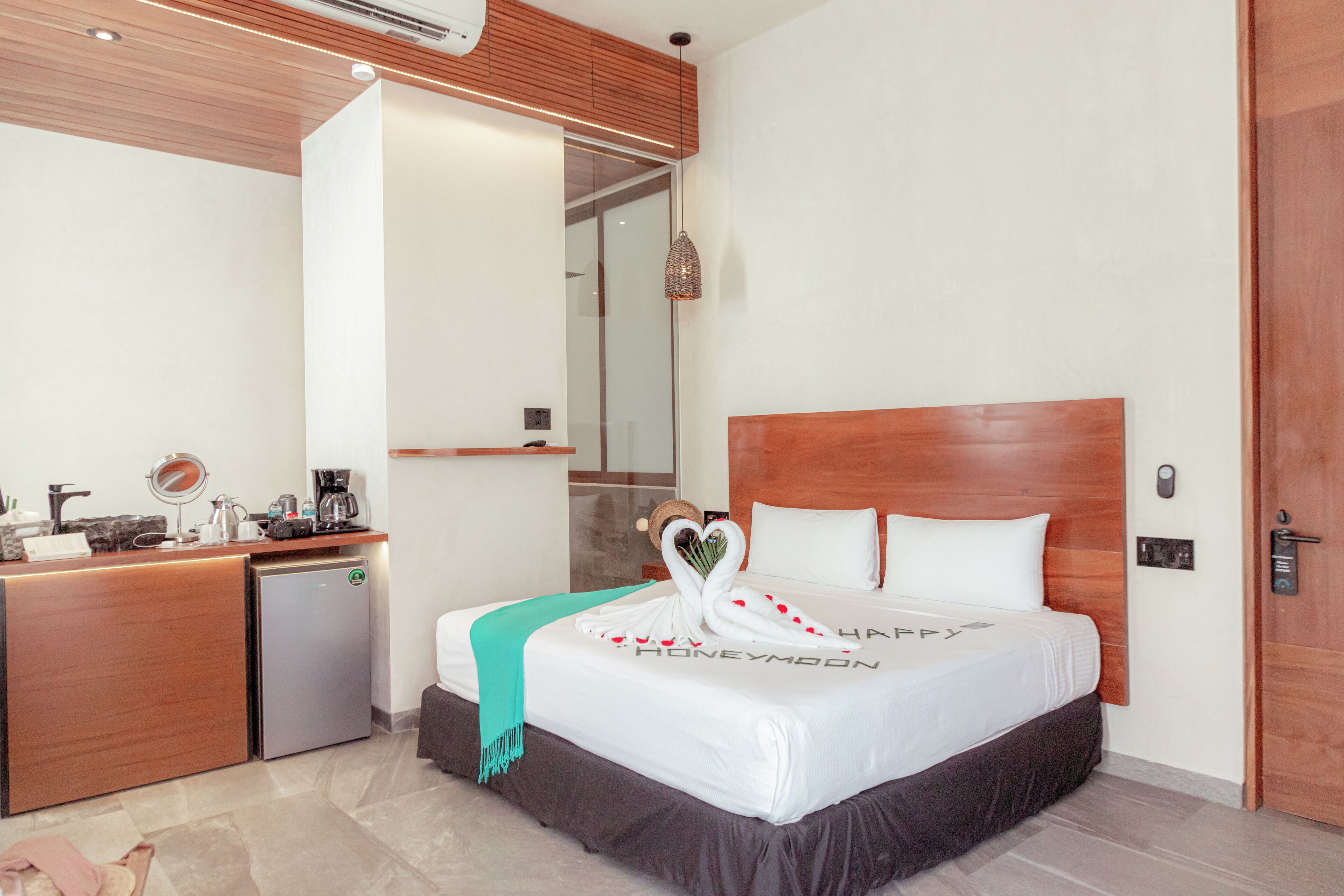 A hotel room with a bed, a small kitchenette, and a wooden headboard.