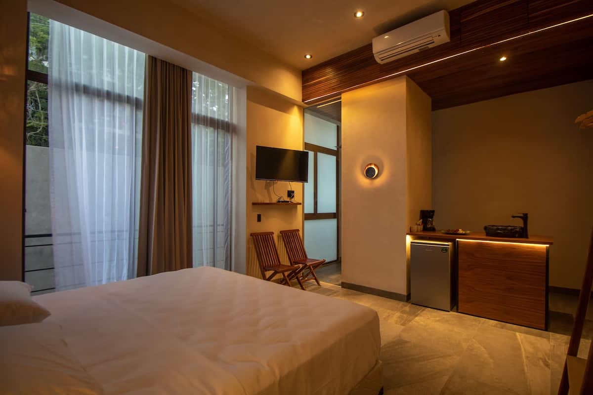 A hotel room with a large bed, a desk with a coffee maker, a TV, and a small refrigerator.