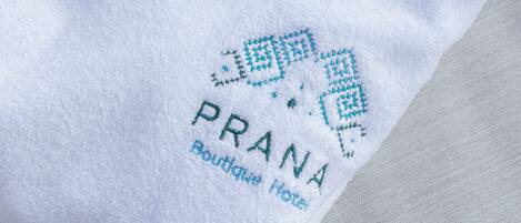 A white towel with a logo and text reading "PRANA Boutique Hotel".