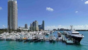 A marina with numerous boats docked, a large cruise ship, and tall buildings in the background. - BeachFront On The Sand Unit #227 South of 5th, 335 Ocean Dr, Miami Beach (Miami Beach)