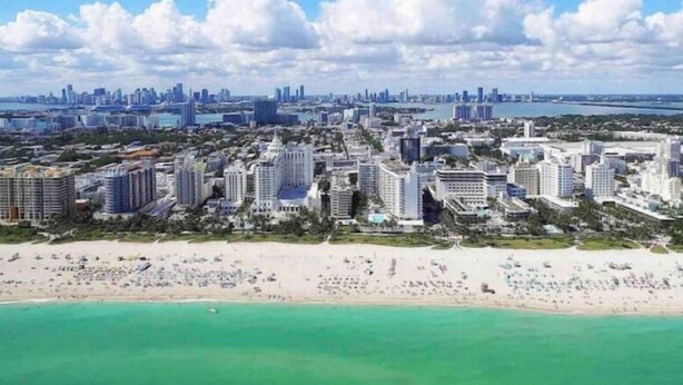 A coastal cityscape with high-rise buildings, a beach, and a marina. - BeachFront On The Sand Unit #227 South of 5th, 335 Ocean Dr, Miami Beach (Miami Beach)