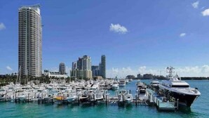 A marina with numerous boats docked, a tall building, and a clear blue sky.