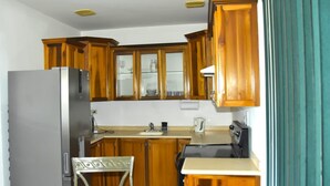 Eine Küche mit Holzausstattung, einem Kühlschrank, einem Herd und einem Spülbecken.