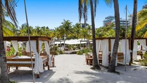 Un resort frente al mar con cabañas de madera, palmeras y un sendero de arena que conduce a la playa.
