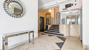 Un vestíbulo moderno con piso de mármol, un espejo redondo y una escalera que lleva a un nivel superior.