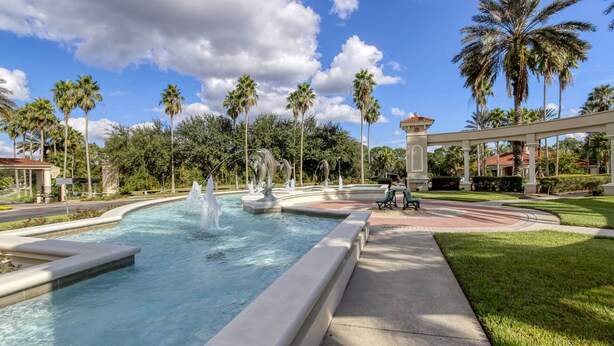 A swimming pool with a fountain, surrounded by palm trees and a gazebo. - Exquisite Townhome in Emerald Island: A Perfect Blend of Luxury and Comfort (Kissimmee)