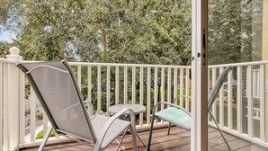 A balcony with a white railing, a metal chair, and a small table. - Exquisite Townhome in Emerald Island: A Perfect Blend of Luxury and Comfort (Kissimmee)