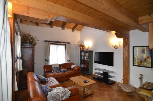 A cozy living room with a brown leather sofa set, a wooden coffee table, a television, and a bookshelf. - Holiday in the Dolomite (Borca di Cadore)