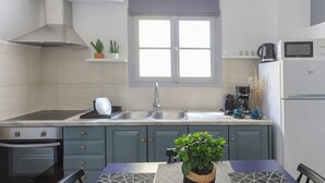 A modern kitchen with a gas stove, sink, and a window above the countertop. - Azul Home - Ahilli Slow Living (Καμάρι)